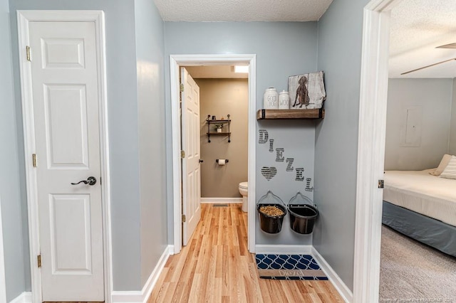 bathroom with wood-type flooring, a textured ceiling, and toilet