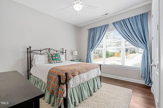 bedroom featuring ceiling fan, wood finished floors, visible vents, and baseboards