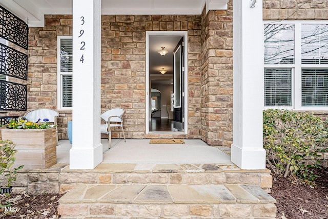 view of exterior entry featuring stone siding and a porch