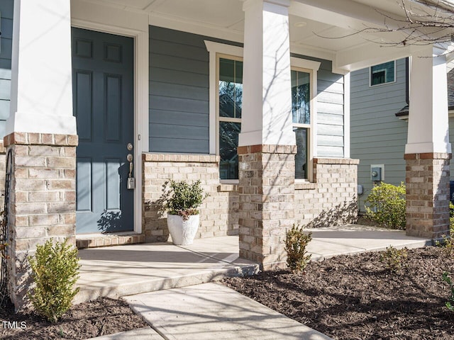 view of exterior entry with covered porch and brick siding