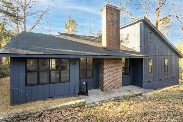 rear view of house featuring crawl space, a chimney, and roof with shingles