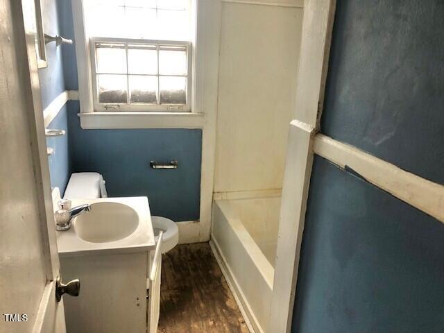 bathroom with vanity, a tub to relax in, hardwood / wood-style floors, and toilet