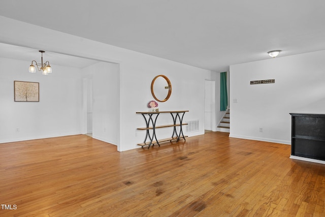 unfurnished living room featuring a notable chandelier and light hardwood / wood-style flooring