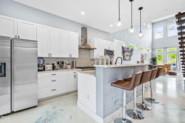 kitchen featuring stainless steel appliances, wall chimney range hood, concrete floors, and decorative backsplash