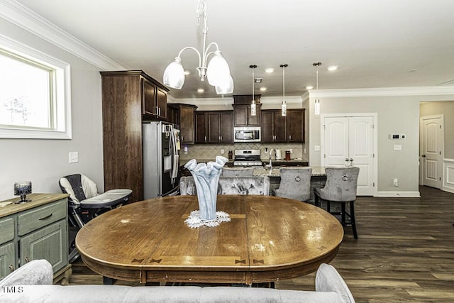 dining area with dark hardwood / wood-style flooring, sink, crown molding, and an inviting chandelier