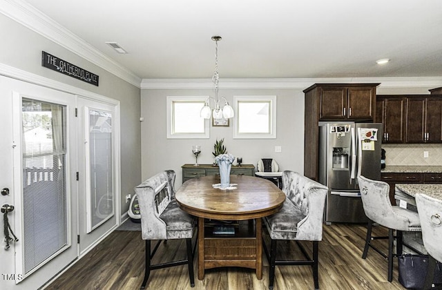 dining room with an inviting chandelier, ornamental molding, and dark hardwood / wood-style flooring