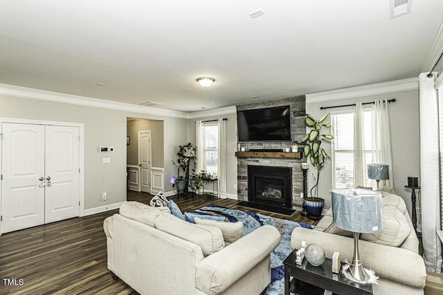 living room with ornamental molding, a stone fireplace, dark wood-type flooring, and a wealth of natural light