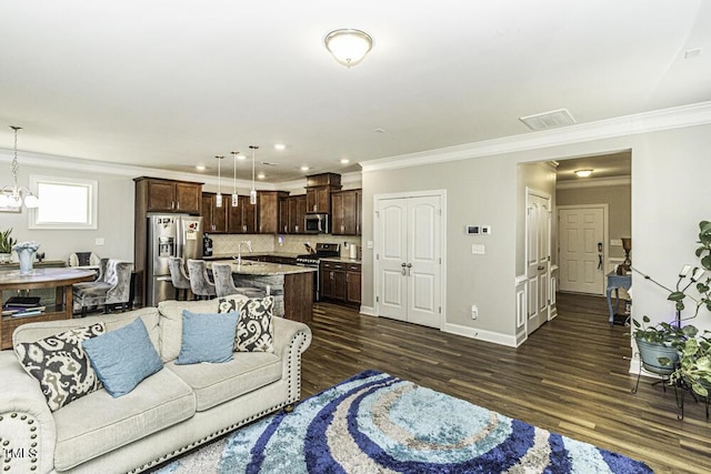 living room with dark hardwood / wood-style flooring, sink, crown molding, and a chandelier