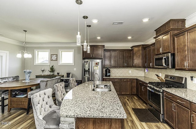 kitchen featuring appliances with stainless steel finishes, sink, a kitchen island with sink, and decorative light fixtures