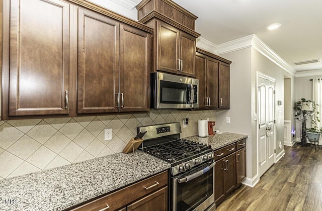 kitchen with crown molding, appliances with stainless steel finishes, light stone countertops, and backsplash