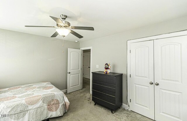 bedroom with ceiling fan, light colored carpet, and a closet