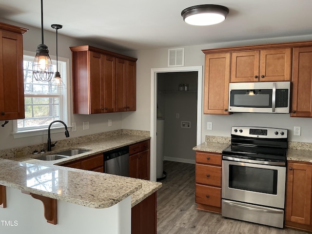 kitchen featuring a breakfast bar, sink, kitchen peninsula, pendant lighting, and stainless steel appliances