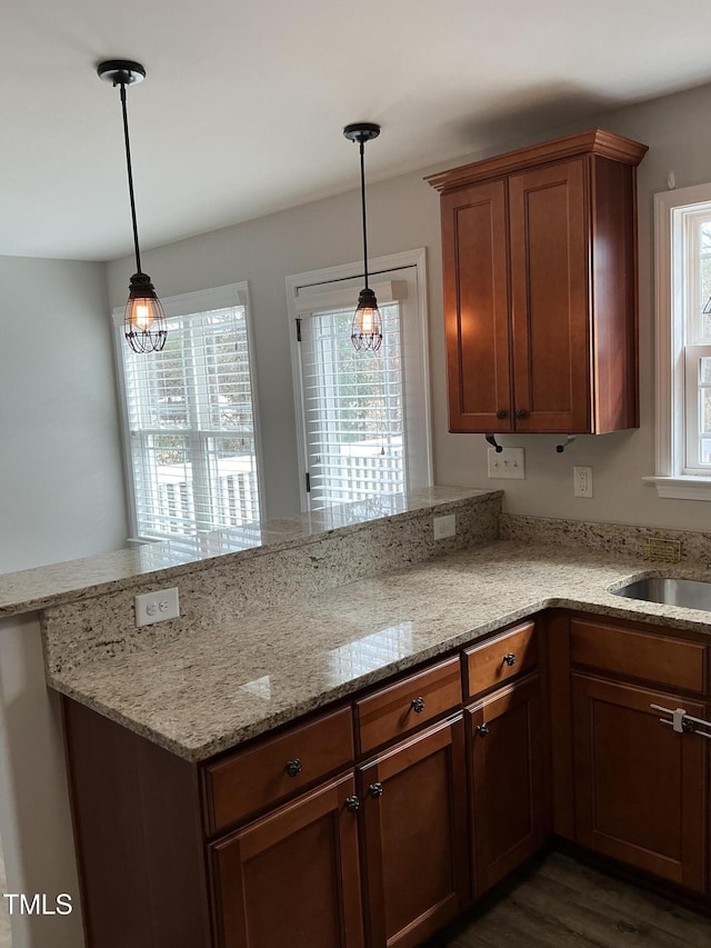 kitchen featuring light stone counters, decorative light fixtures, and kitchen peninsula