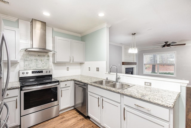 kitchen with appliances with stainless steel finishes, white cabinetry, sink, kitchen peninsula, and wall chimney exhaust hood