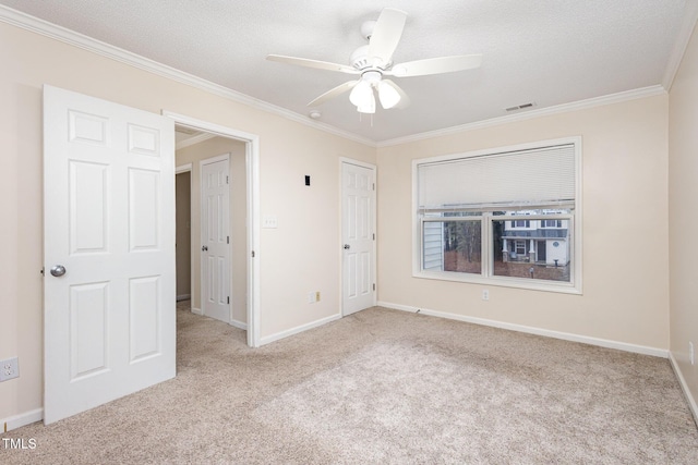 carpeted spare room featuring crown molding, a textured ceiling, and ceiling fan