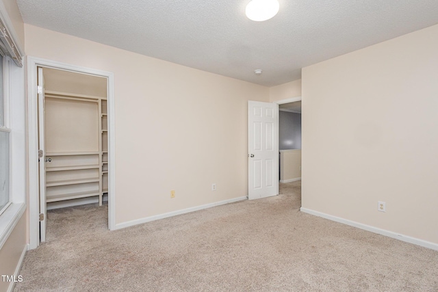 unfurnished bedroom featuring a spacious closet, light colored carpet, and a textured ceiling