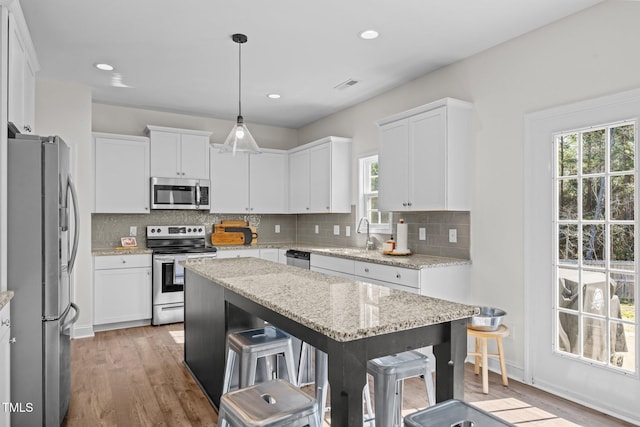 kitchen featuring white cabinetry, decorative light fixtures, and appliances with stainless steel finishes