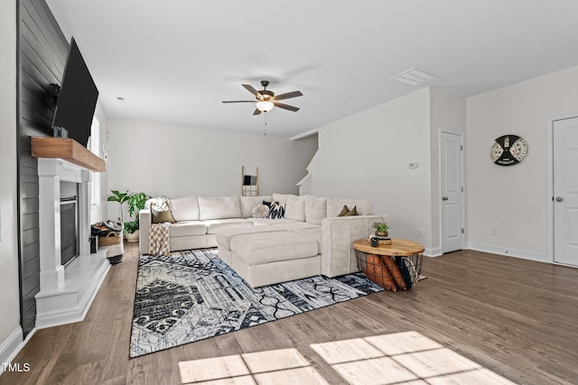 living room with a large fireplace, hardwood / wood-style floors, and ceiling fan