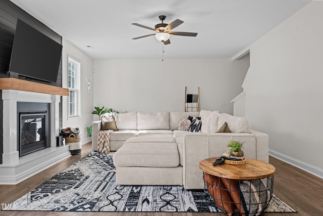 living room featuring a large fireplace, dark hardwood / wood-style floors, and ceiling fan