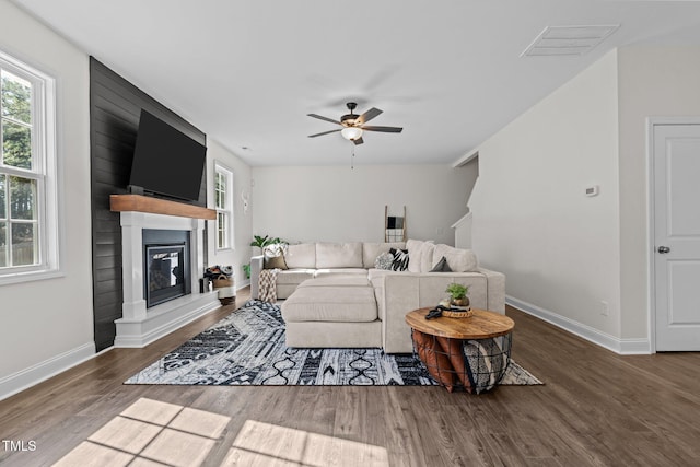 living room with a fireplace, a wealth of natural light, dark hardwood / wood-style floors, and ceiling fan