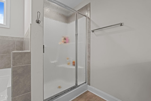 bathroom with a shower with door and wood-type flooring