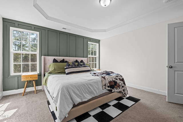 bedroom featuring light carpet, a tray ceiling, and ornamental molding