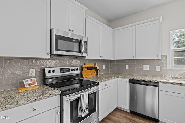 kitchen featuring white cabinetry, decorative backsplash, stainless steel appliances, and light stone counters