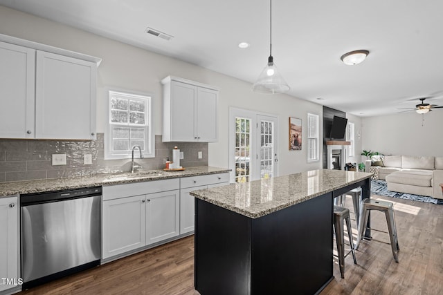 kitchen with pendant lighting, sink, white cabinetry, a kitchen island, and stainless steel dishwasher