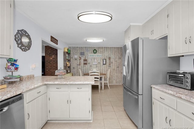 kitchen with light tile patterned flooring, appliances with stainless steel finishes, kitchen peninsula, and white cabinets