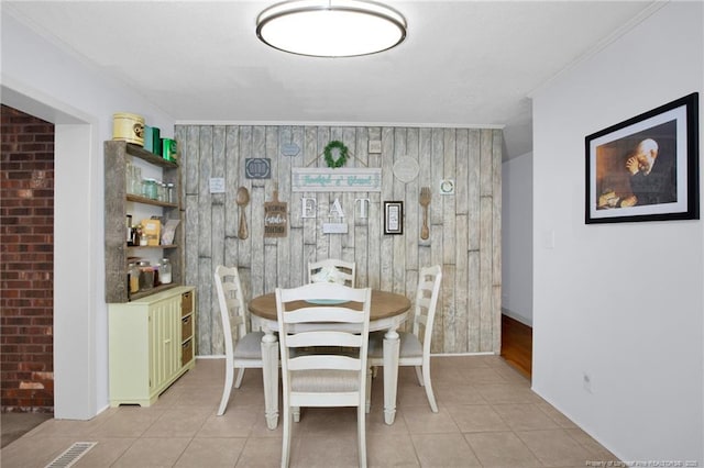 dining room featuring ornamental molding, brick wall, and light tile patterned floors