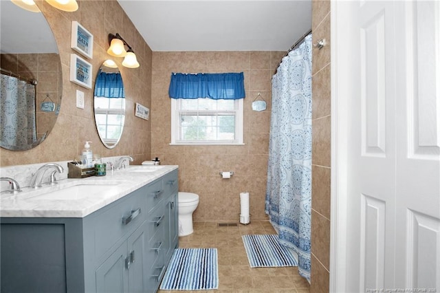 bathroom featuring tile walls, vanity, tile patterned flooring, and toilet