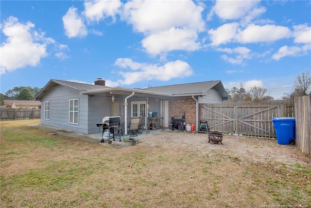 back of house with french doors, a lawn, a patio, and an outdoor fire pit