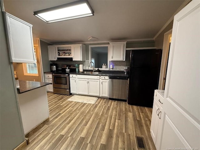 kitchen featuring sink, appliances with stainless steel finishes, white cabinetry, backsplash, and light wood-type flooring