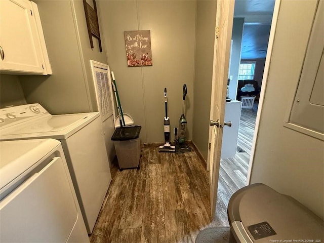 washroom with cabinets, washing machine and dryer, and dark hardwood / wood-style flooring