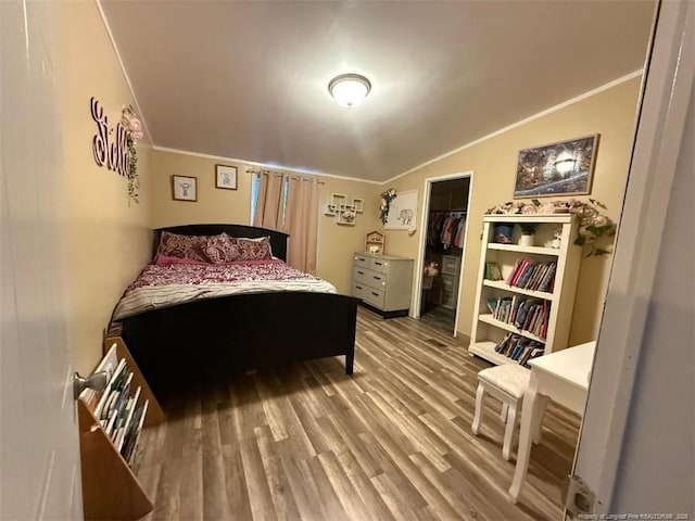 bedroom with vaulted ceiling, crown molding, hardwood / wood-style floors, and a closet