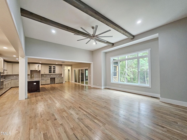 unfurnished living room featuring ceiling fan, light hardwood / wood-style flooring, and beamed ceiling