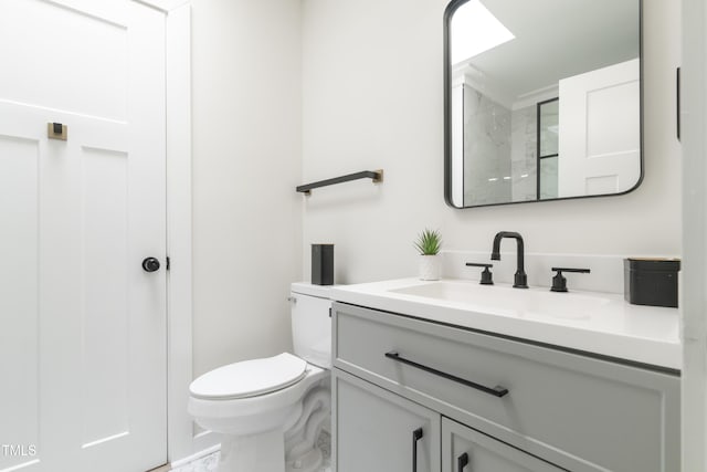 bathroom with toilet, marble finish floor, and vanity