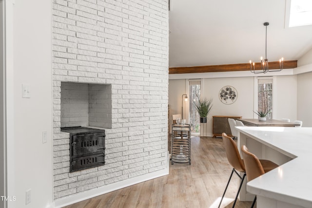 dining area featuring a notable chandelier, light wood-style flooring, and brick wall