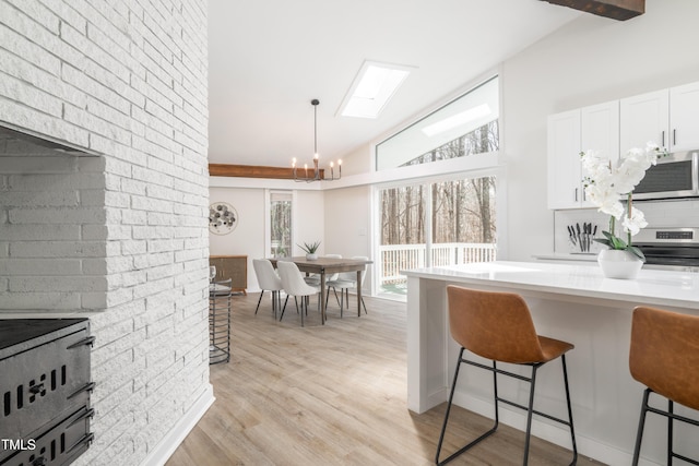 kitchen featuring lofted ceiling, light wood-style flooring, a breakfast bar area, stainless steel appliances, and light countertops