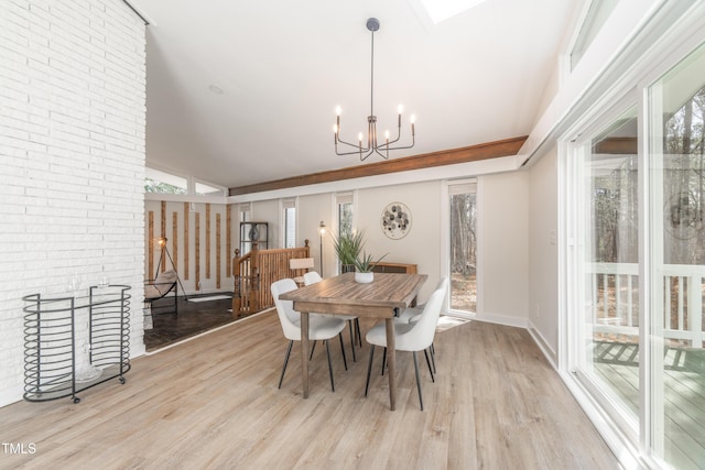 dining space with brick wall, light wood-style flooring, baseboards, and a notable chandelier