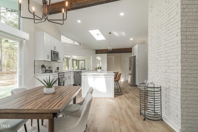 kitchen featuring a skylight, light wood finished floors, light countertops, appliances with stainless steel finishes, and white cabinets