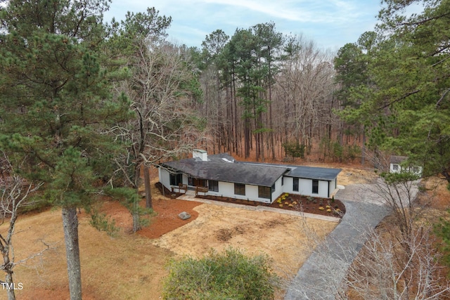 ranch-style home with driveway and a view of trees