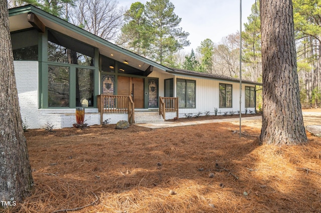 mid-century inspired home featuring covered porch and brick siding