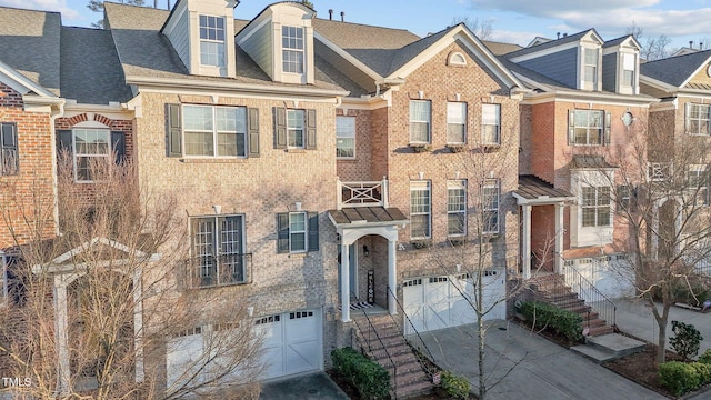 townhome / multi-family property with an attached garage, concrete driveway, and brick siding