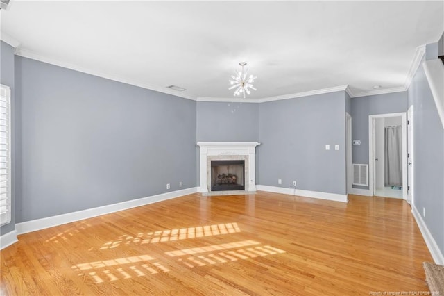 unfurnished living room featuring crown molding, a fireplace, light hardwood / wood-style floors, and a chandelier