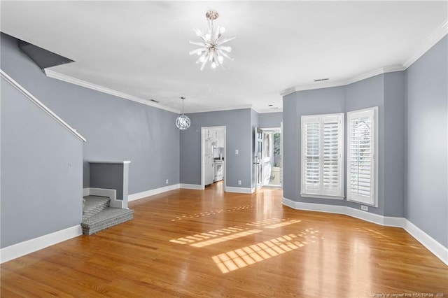 unfurnished living room featuring crown molding, hardwood / wood-style floors, and a chandelier