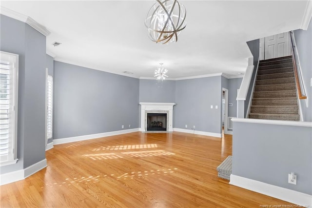 unfurnished living room featuring ornamental molding, wood-type flooring, and an inviting chandelier