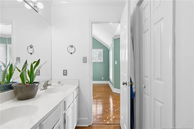 bathroom featuring ornamental molding, vaulted ceiling, hardwood / wood-style floors, and vanity