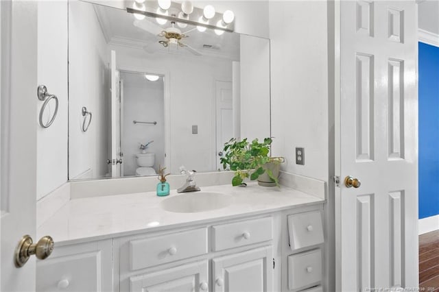 bathroom with ornamental molding, vanity, toilet, and hardwood / wood-style floors