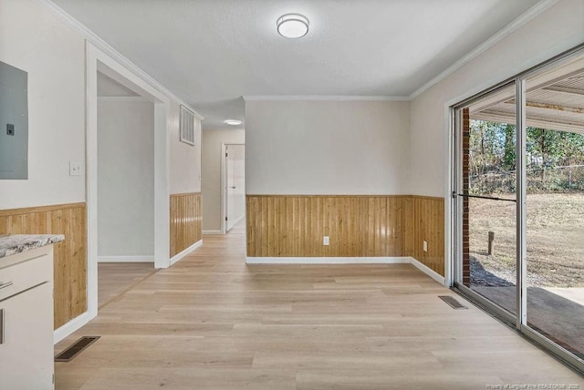 unfurnished room featuring a wainscoted wall, visible vents, wood walls, and ornamental molding